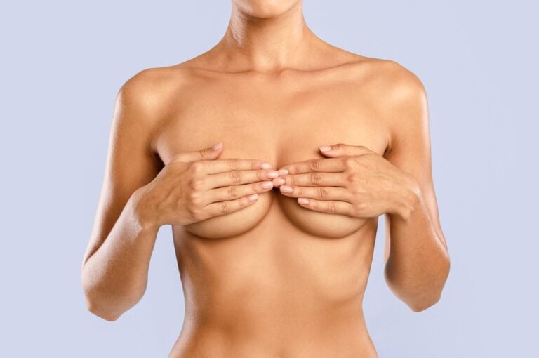 woman covers breasts with hands